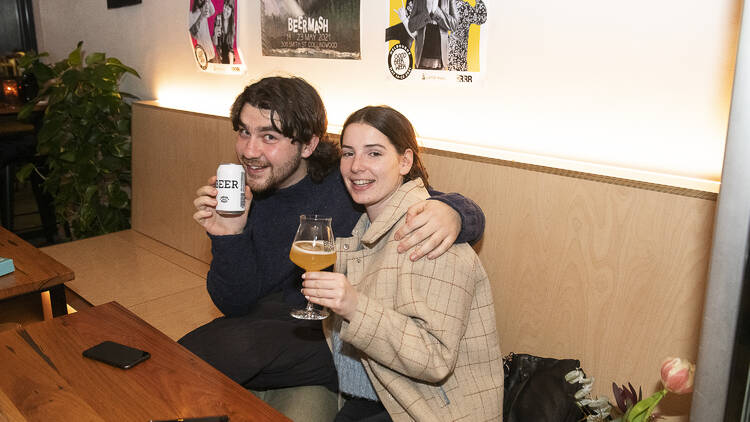 A couple enjoying glasses of. beer a table inside a bar.