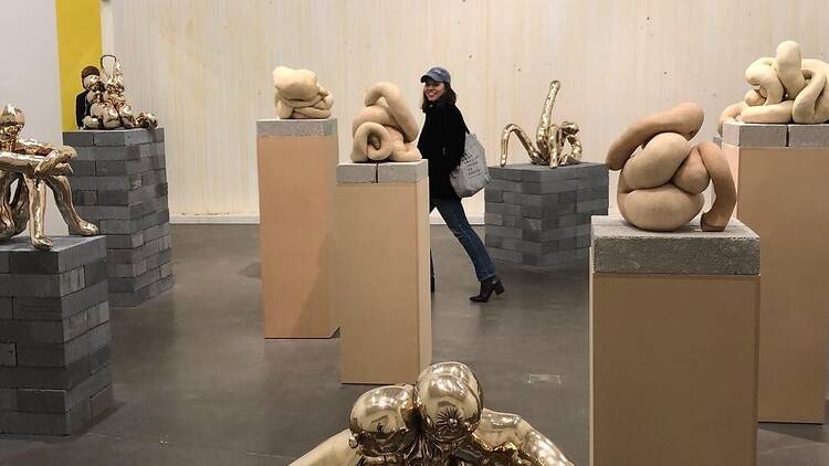 A person walks through a room with sculptures.