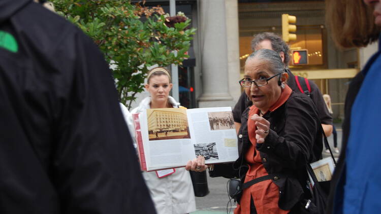 A tour guide holds up a book.