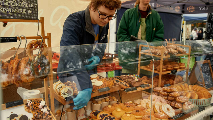 A person grabbing a pastry from a cabinet of baked goods.