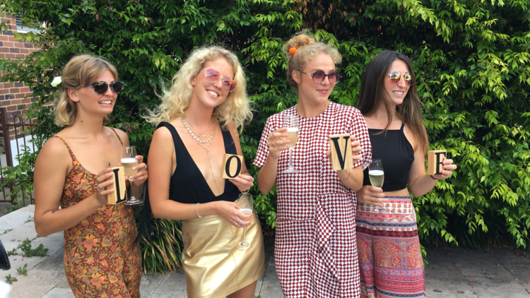 Four women with glasses of champagne holding the letters that spell out LOVE
