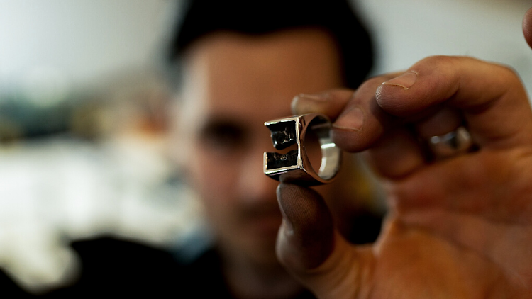 A person holds up a silver ring.