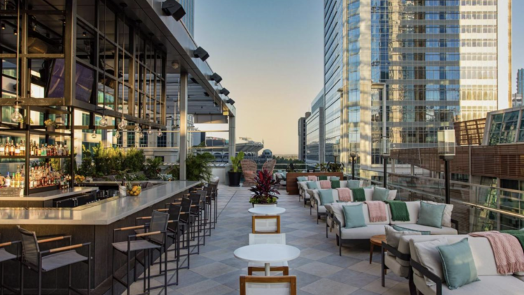 hotel roof terrace with an outdoor bar, seating and city views