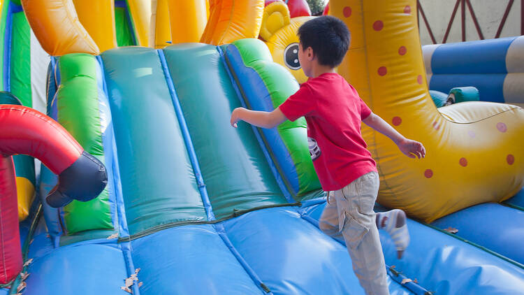 Niño con playera roja corriendo en inflable 