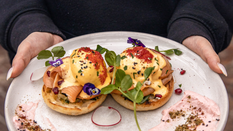 Beautiful-looking eggs Benedict with smoked salmon and garnishes.