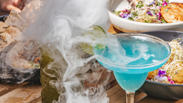 A blue cocktail with smoke flowing off it.