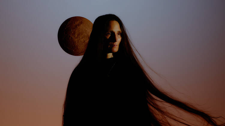 picture of a woman and a moon is behind her