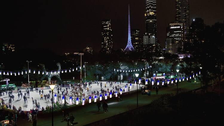 An ice skating rink at night in Melbourne with the Arts Centre Melbourne in the background 