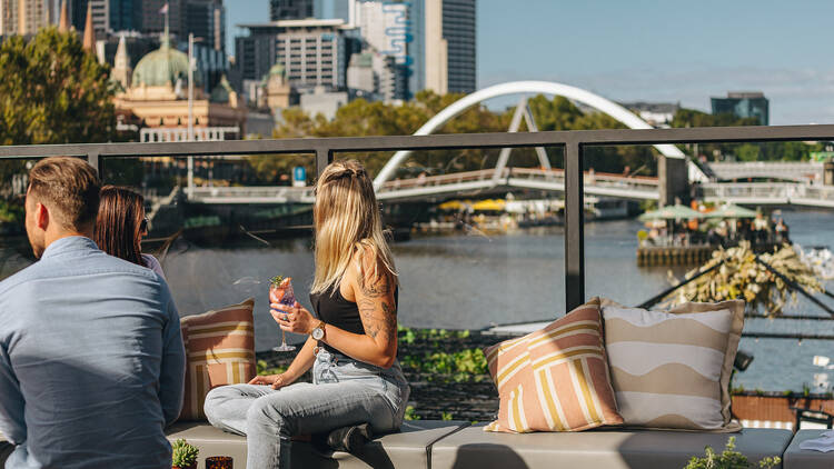 Blonde woman drinking at a riverside bar. 