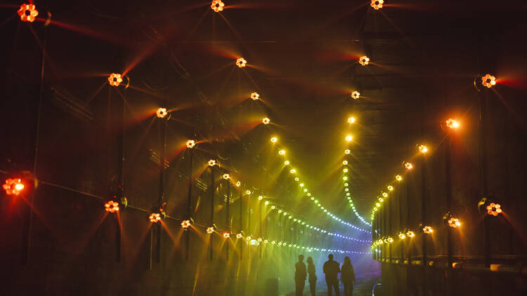 A dark tunnel filled with rainbow lights.