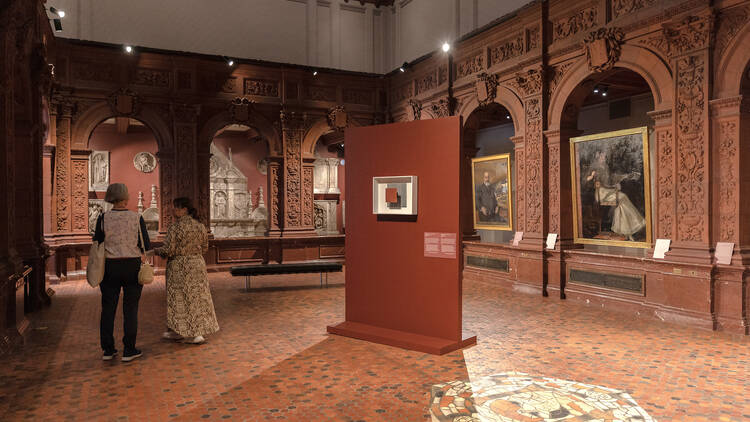 Two people walk through a gallery at the Hispanic Society.