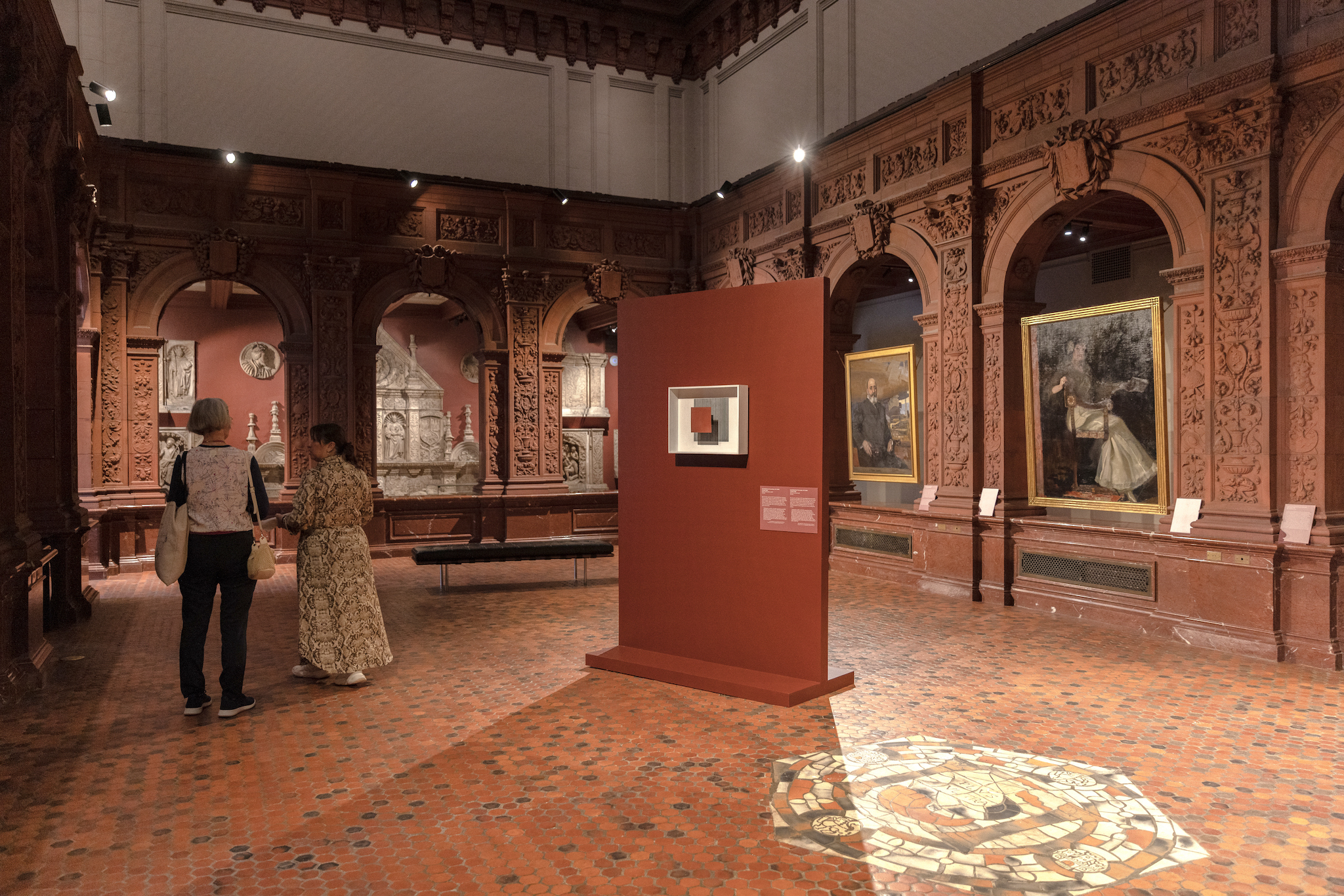 Two people walk through a gallery at the Hispanic Society.