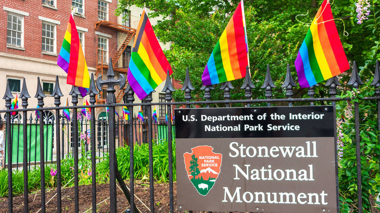 Stonewall National Monument sign on the fence decorated with rainbow flags at Christopher Park in Greenwich Village -