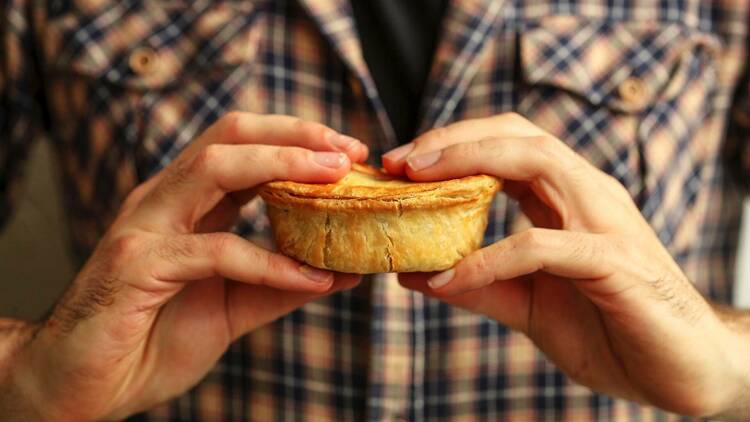 A person holding a meat pie