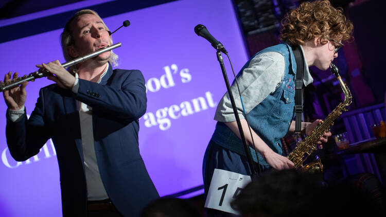 Ian Lockwood, in a blue suit, plays the flute. Another performer plays the saxophone.