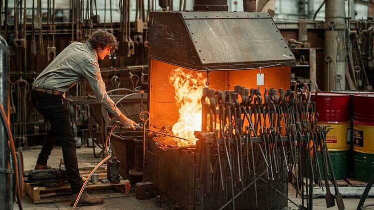 A man puts a metal implement into a fire.