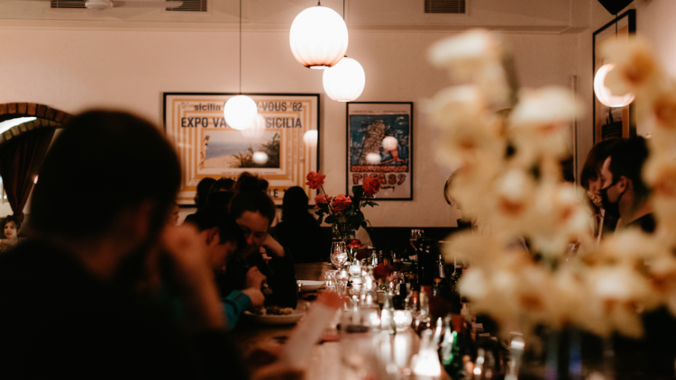 The interior of a crowded Italian restaurant with people sitting at a bar.