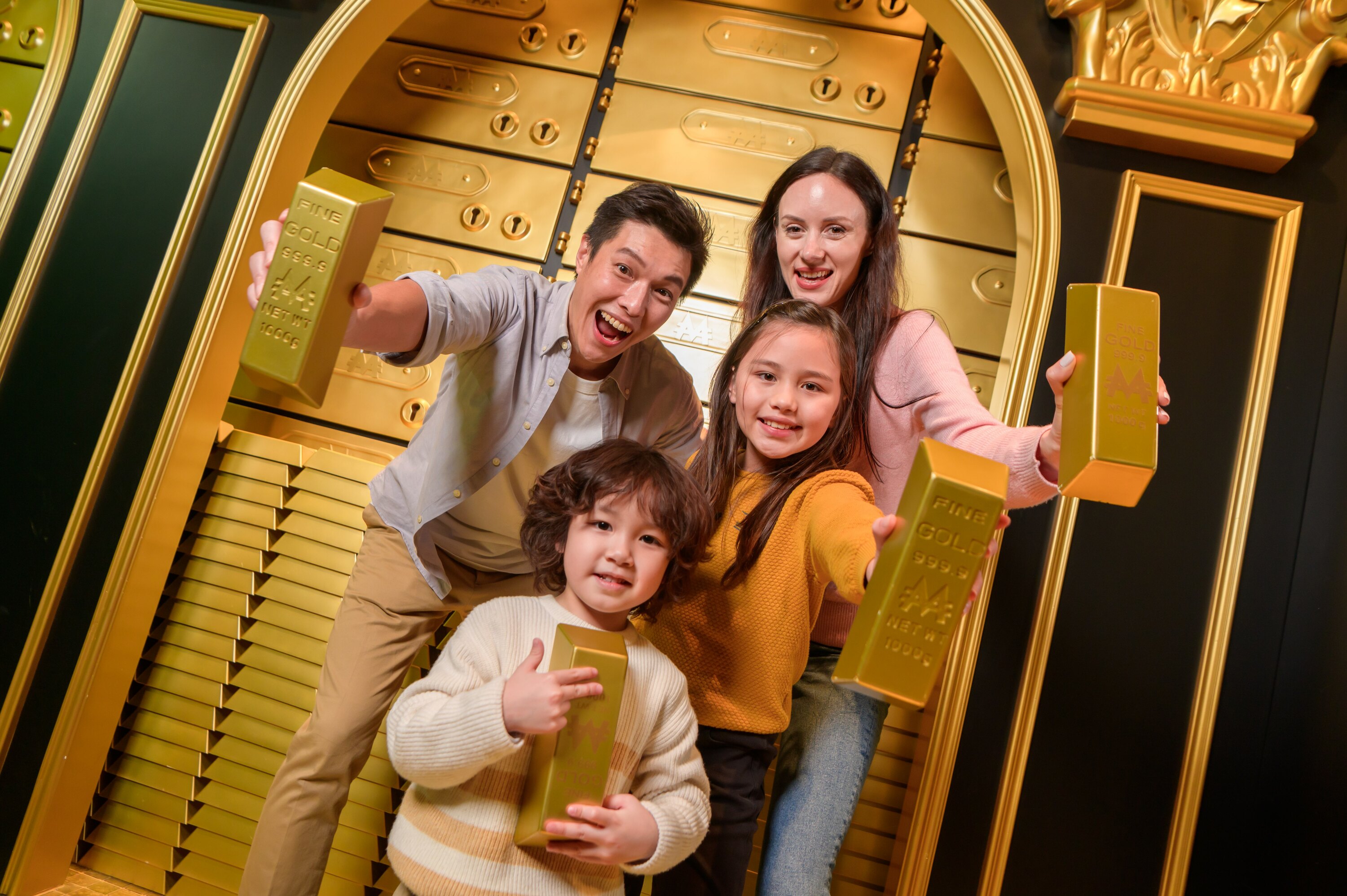 A family posing with gold bullions in front of more gold.
