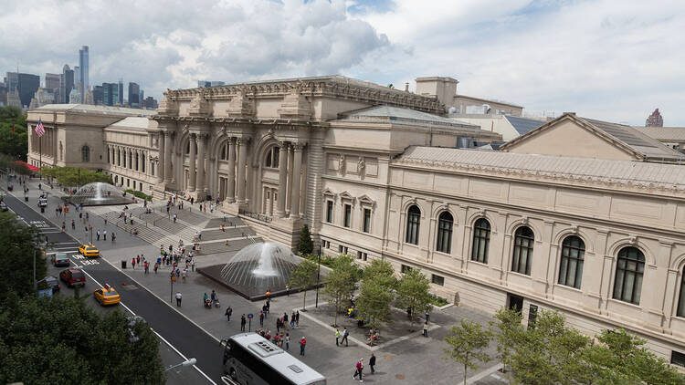 An exterior view of the Met Museum with a fountain out front.