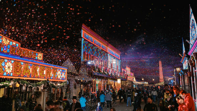 Sovereign Hill at night, with illuminated buildings and snow falling.