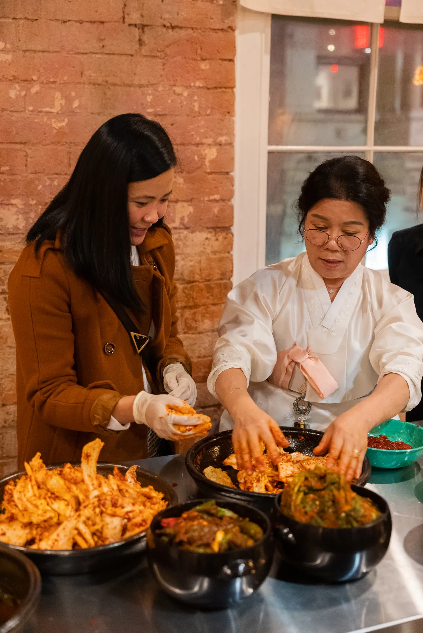 Korean grandmother teaching event guest how to make kimchi.