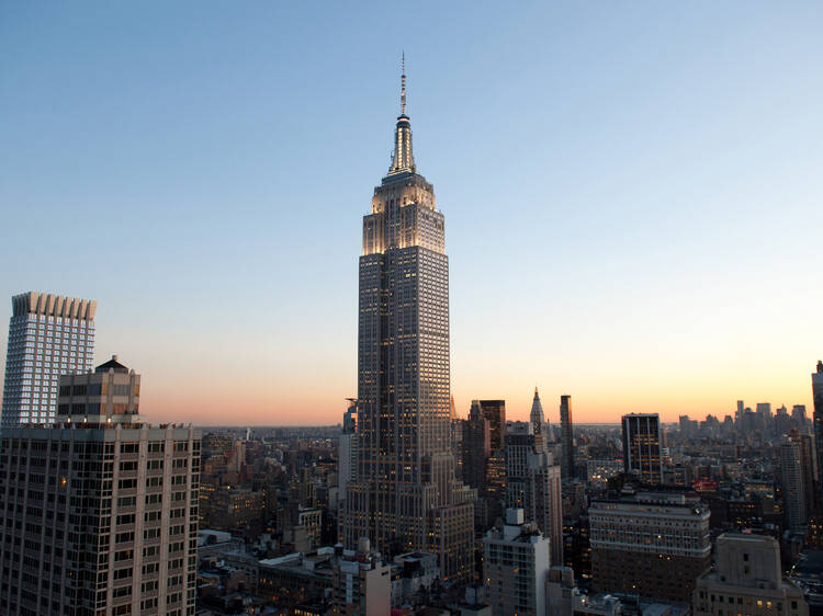 The Empire State Building lit up with the skyline in the background.