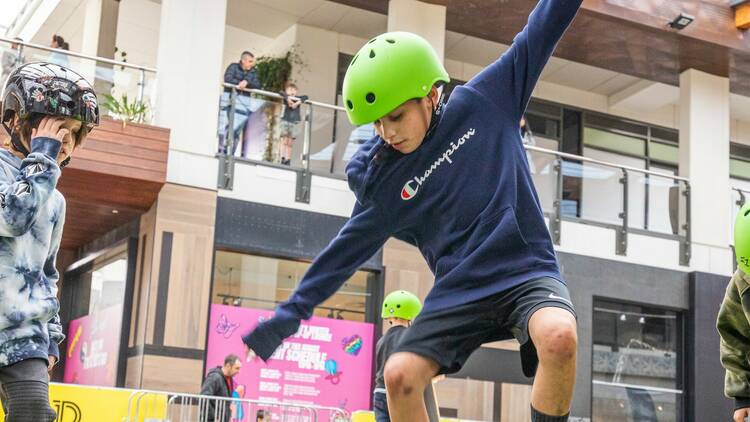 A young child wearing a neon green helmet uses a skateboard