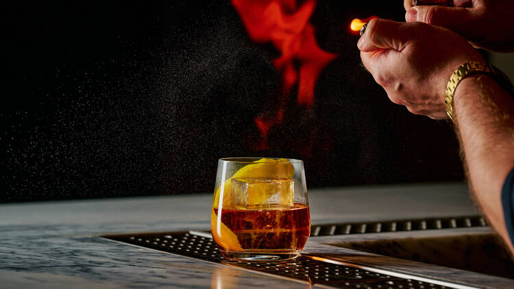 Bartender setting a cocktail on fire.
