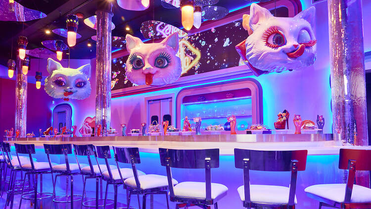SUSHIDELIC’s long, curving bar that has huge cat faces hanging above it.