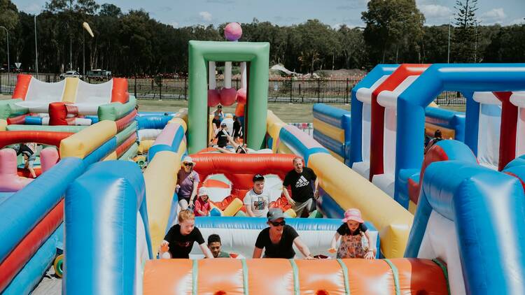 Kids and adults climb a large inflatable obstacle course