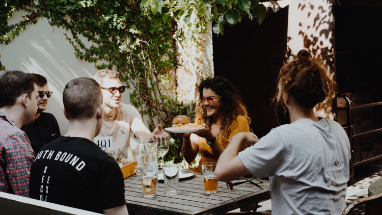 A group of friends laughing and drinking beer in a beer garden.