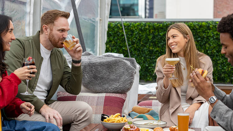 Smiling friends eating and drinking in a marquee.