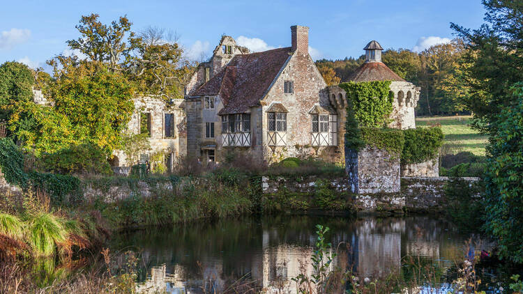 Scotney Castle reflected on the water in Tunbridge Wells, surrounded by trees