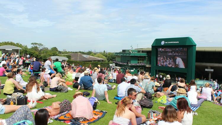 Crowd watching Wimbledon on a screen outside 
