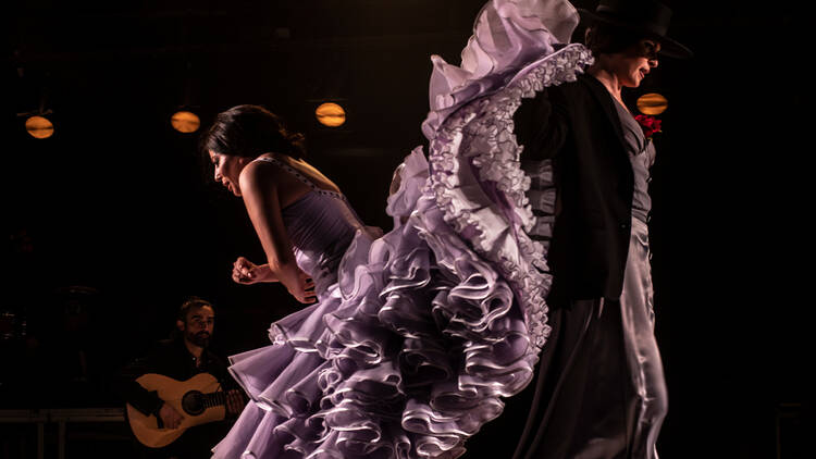 Mercedes de Córdoba dancing in a purple dress with a flowing frilly skirt 