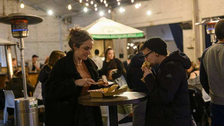 Two people eating at a night market.