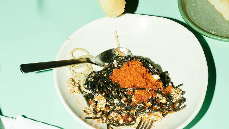 Someone eating a bowl of pasta with bread.