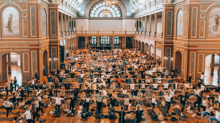 A lot of people doing yoga in a hall