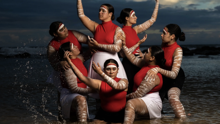 An Aboriginal Australian dance group in a body of water.