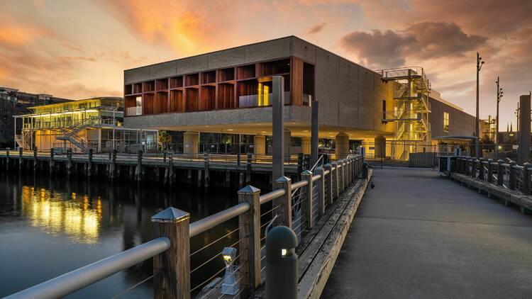 Museum at the wharf with sunset behind it.