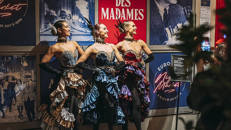 Three dancers in flamboyant dresses mid-performance. 