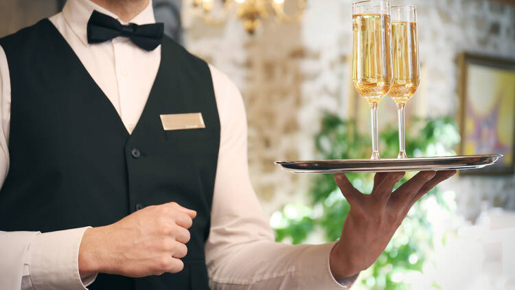 Waiter serving champagne at restaurant, close up view