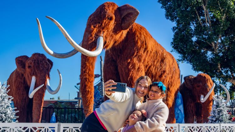 People pose in front of a mammoth
