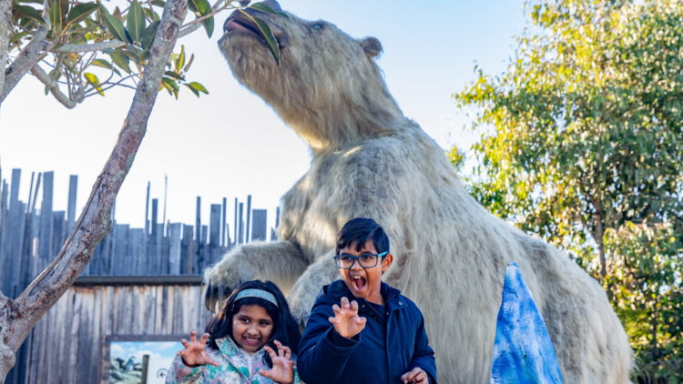 Kids smile in front of a giant sloth 