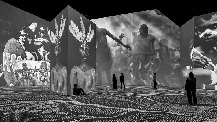Black and white photographs of Indigenous people projected in a digital gallery.
