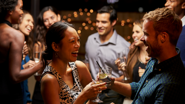 A couple laugh holding drinks