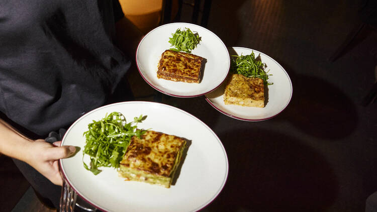 Three plates of lasagne and salad.