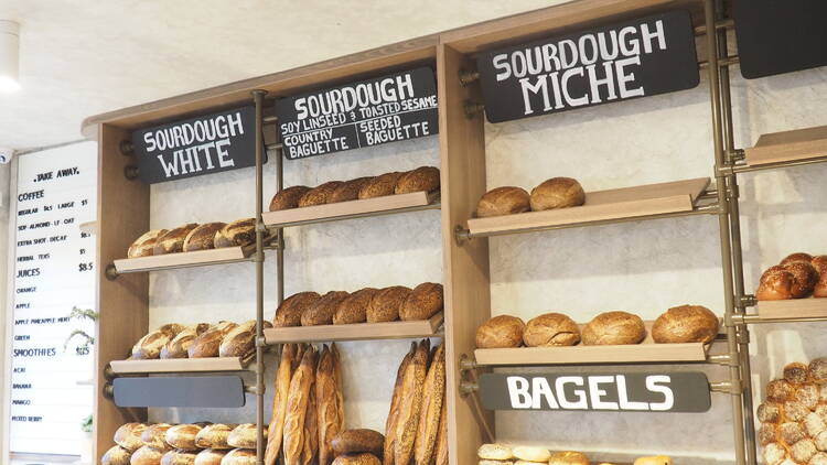 A bakery wall with shelves full of bread.