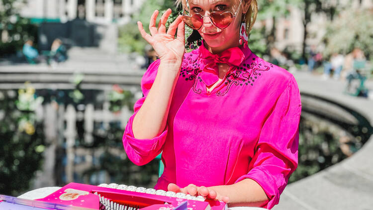 A woman dressed in a pink outfit at a pink typewriter.