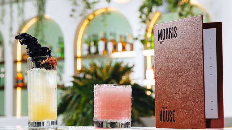 Two cocktails on a bar next to a menu branded 'Morris House'.